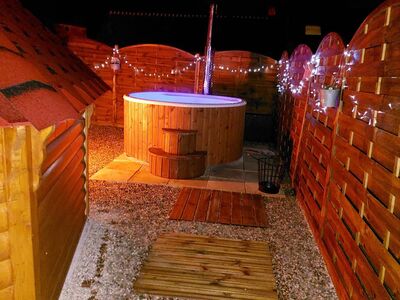 Bain nordique en bois illuminé de nuit avec guirlandes lumineuses