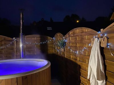 Bain nordique en bois éclairé en bleu la nuit avec guirlandes