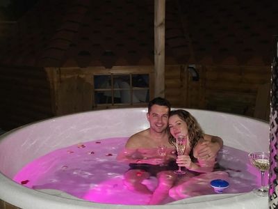 Couple dans le bain nordique avec éclairage rose et champagne