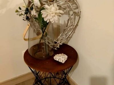 Vase de fleurs blanches et cœur décoratif sur guéridon