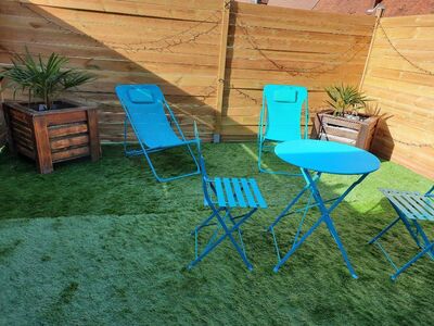 Salon de jardin bleu sur gazon avec clôture bois