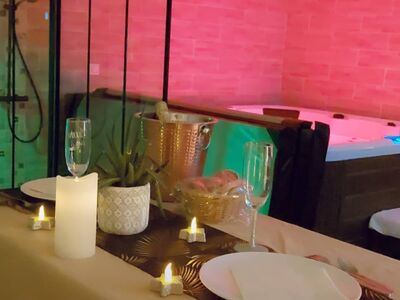Table romantique avec bougies, champagne et jacuzzi éclairé en rose